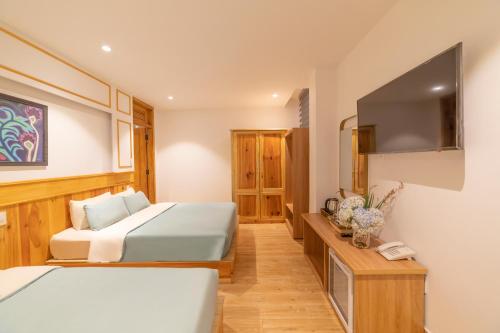a bedroom with two beds and a flat screen tv at Pham Gia Dalat Villa & Hotel in Da Lat