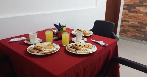 Hotel Coffee Real Pereira في بيريرا: طاولة مع أطباق من الطعام وكؤوس من عصير البرتقال