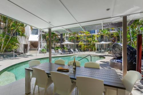 a dining area with a table and chairs next to a pool at Noosa Tropicana in Noosaville