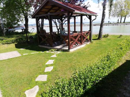 a wooden gazebo on the grass near the water at Ház a szígeten in Fonyód