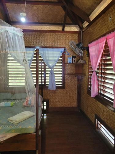 a bedroom with two windows and a bed with mosquito nets at MALAIKA RESORT in San Vicente