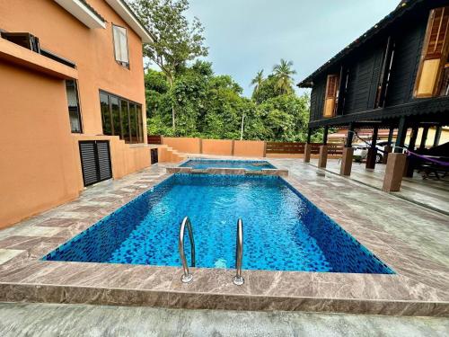 a swimming pool in front of a house at Villa Bani Hashim in Pantai Cenang