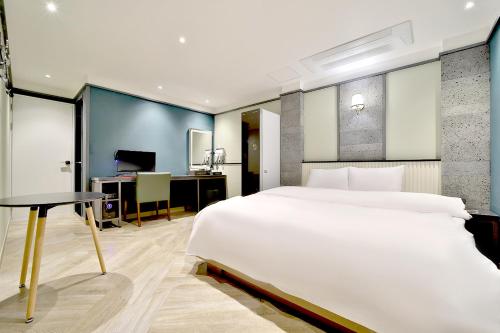 Deagu Hotel Rubato RB في دايغو: غرفة نوم مع سرير أبيض كبير ومكتب