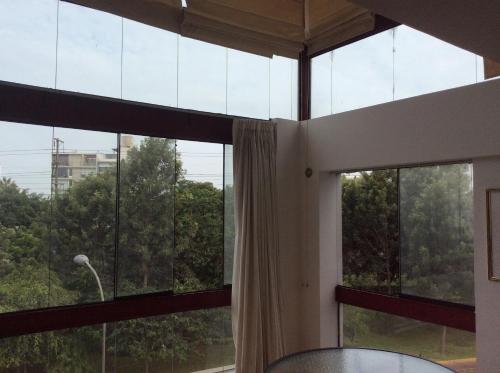 Zimmer mit großen Fenstern, Vorhängen und einem Tisch in der Unterkunft Departamento Dúplex in Lima