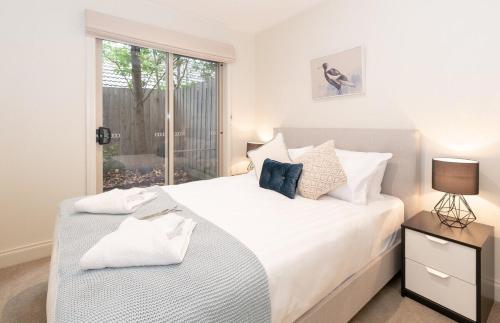 sypialnia z dużym białym łóżkiem i oknem w obiekcie Harp Haven - Contemporary in Suburban Tree lined Kew w Melbourne