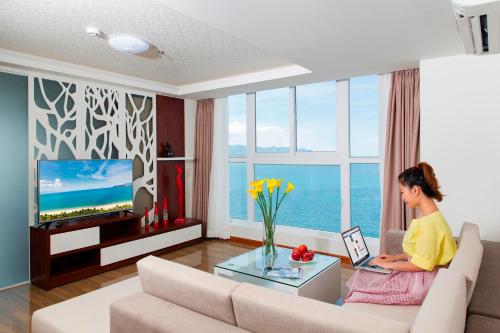 a woman sitting on a couch in a living room at Paris Nha Trang Hotel in Nha Trang