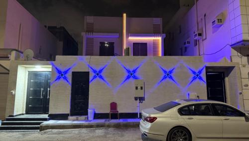 un coche blanco estacionado frente a un edificio con luces azules en شاليهات السلطان 3 غرف قريبه من الحرم بحي الملك فهد, en Sīdī Ḩamzah