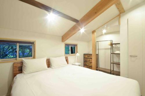 - une chambre avec un grand lit blanc et 2 fenêtres dans l'établissement Hakuba Hoshikage - beautiful mountain cottage, à Hakuba