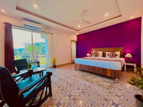 a bedroom with purple walls and a bed and a bench at The Four Season Hotel & Cottage, Goa in Candolim