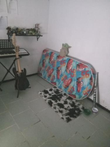 una valigia seduta nell'angolo di una stanza con chitarra di Hostal puebla a Lomas de Angelopolis