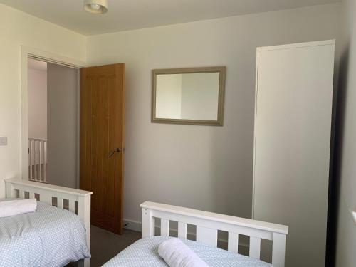a bedroom with two beds and a mirror on the wall at The Chestnuts in Winscombe