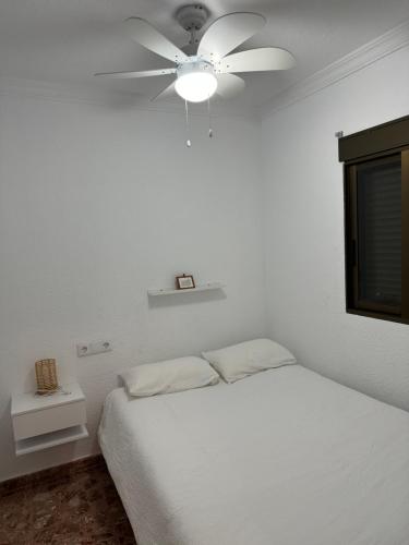 een slaapkamer met een wit bed en een plafondventilator bij Playa Villajoyosa, apartamento in Villajoyosa