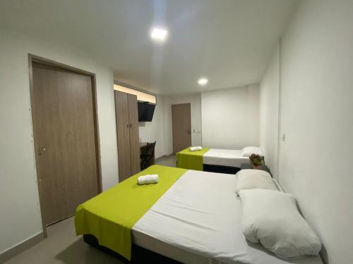 a bedroom with two beds with green and white sheets at Emporium Medellín Laureles in Medellín
