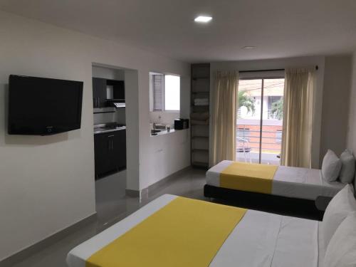 a bedroom with two beds and a tv and a kitchen at Emporium Medellín Laureles in Medellín