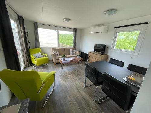 ein Wohnzimmer mit einem Tisch und grünen Stühlen in der Unterkunft Camping Wad noch Meer in Anna Paulowna