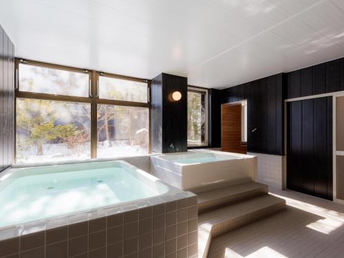 a bathroom with a large tub and a large window at Tabist Kitami Athlete Stays in Kitami