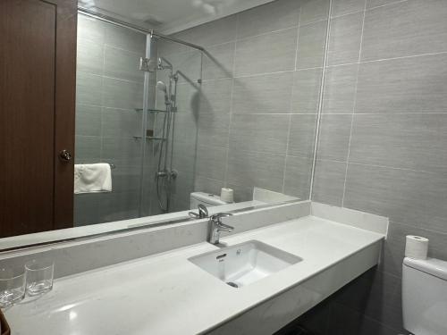 Baño blanco con lavabo y espejo en Ngoc Thu Palace, en Soc Trang