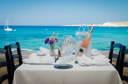 a table with a bottle of wine and glasses on the beach at Hotel L'ondine in Algajola