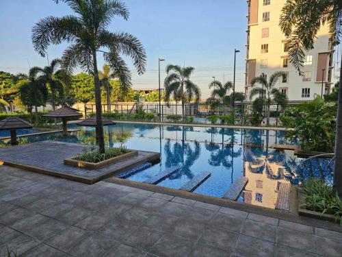 une grande piscine bordée de palmiers et un bâtiment dans l'établissement Shanata Suntrust, à Manille