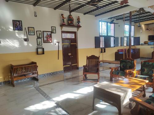 una habitación con sillas y mesas en una habitación en Maha Periyava Kuteeram en Kumbakonam