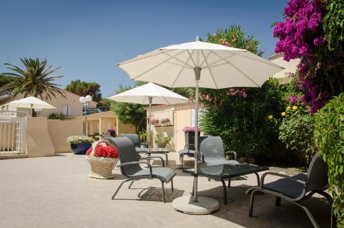 a patio with chairs and a table and an umbrella at Hotel L'ondine in Algajola