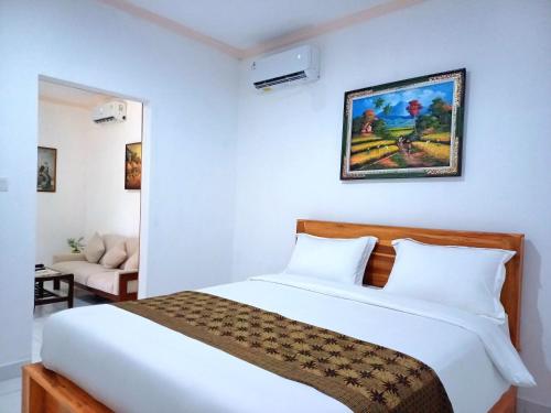 um quarto com uma grande cama branca e um sofá em Rumah Bali Kelating em Krambitan