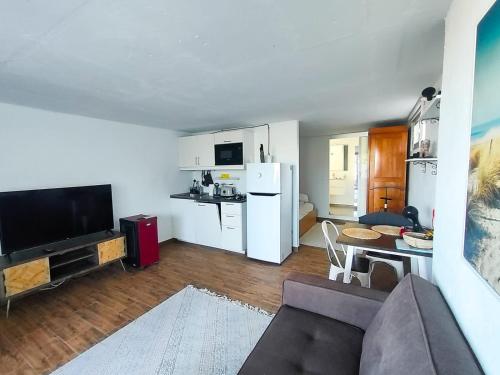 ein Wohnzimmer mit einem Sofa und eine Küche mit weißen Geräten in der Unterkunft Haus mit fantastischem Meerblick in Mácher