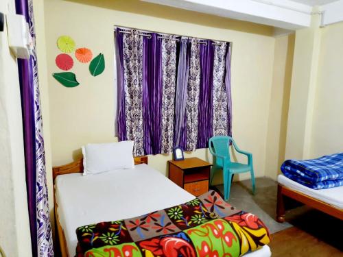 a room with two beds and a window with purple curtains at Travellers' Den in Darjeeling