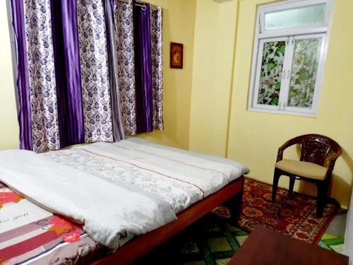 a bedroom with a bed and a window and a chair at Travellers' Den in Darjeeling