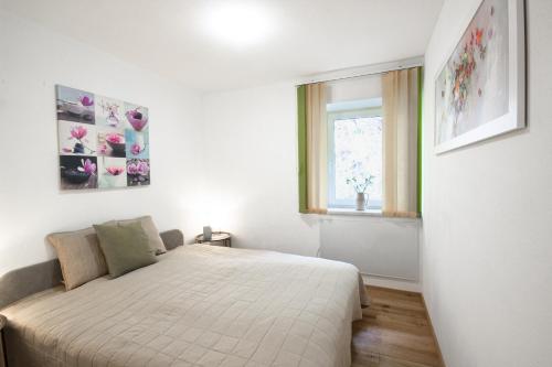 a white bedroom with a bed and a window at Appartement Riedingtal in Zederhaus