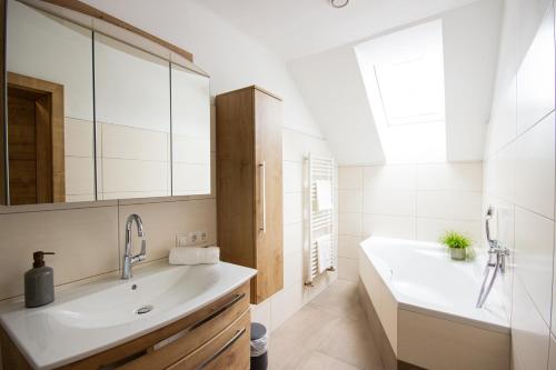 a bathroom with a sink and a tub and a mirror at Appartement Riedingtal in Zederhaus