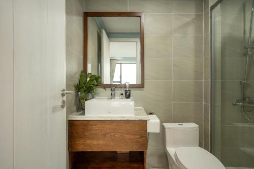 a bathroom with a sink and a toilet and a mirror at DingD0ng Home FelizEnVista 5-star facilities in Ho Chi Minh City