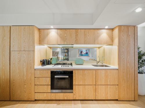 a kitchen with wooden cabinets and a sink at Bondi Pacific Studio - Managed by X Hospitality in Sydney