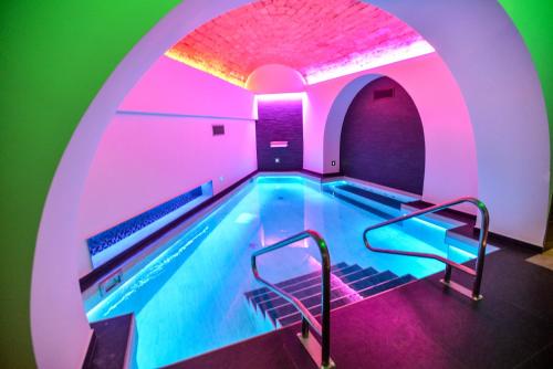 una piscina coperta con illuminazione viola e verde di THE ONE Boutique Hotel & SPA Rome a Roma