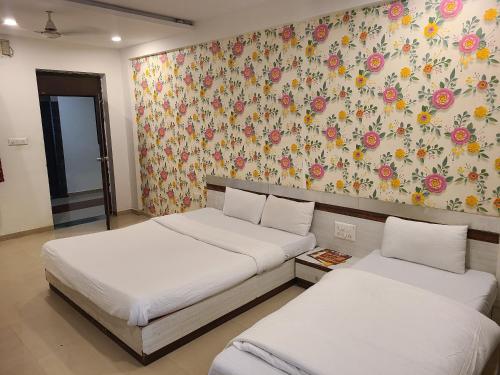 アーメダバードにあるHotel Motera Innの花柄の壁紙を用いた客室内のベッド2台