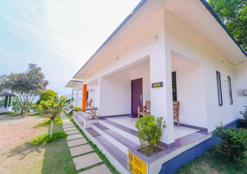 a white house with a pathway leading up to it at Vythiri Silver Mist Villa by VOYE HOMES in Vythiri