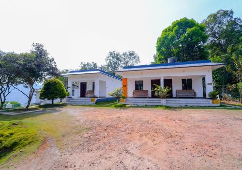 a small white house with a dirt road in front at Vythiri Silver Mist Villa by VOYE HOMES in Vythiri