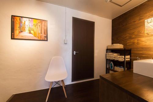 a bathroom with a black door and a white chair at ガジュマルの庭～itoman in Ō