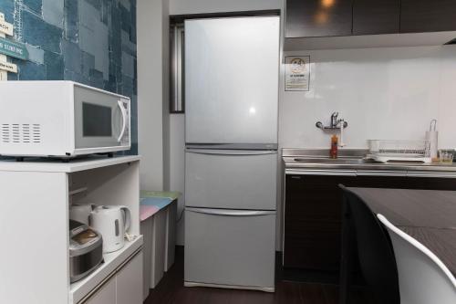 a kitchen with a refrigerator and a microwave at ガジュマルの庭～itoman in Ō