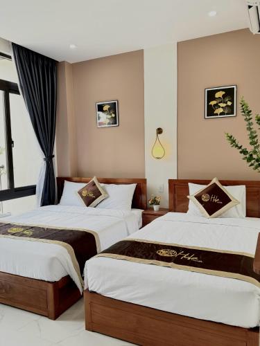 a bedroom with two beds and a window at Hula Hotel in Can Tho