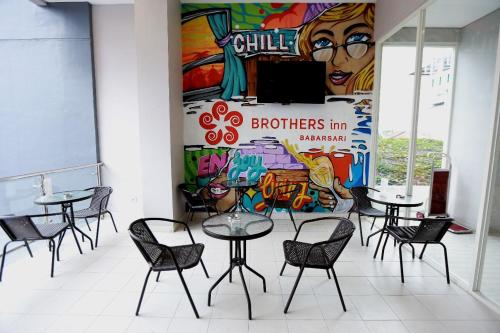 a group of tables and chairs in a room with a mural at Hotel Brothers Inn Babarsari in Seturan
