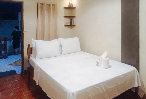 een bed met witte lakens en kussens in een kamer bij RedDoorz at Amphibi-ko Resort Palawan in Coron