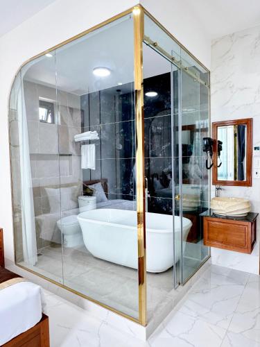 a bathroom with a tub and a glass shower at Hula Hotel in Can Tho