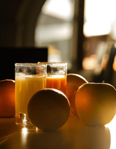 two oranges and a glass of orange juice on a table at Hôtel Du Golfe in Ajaccio