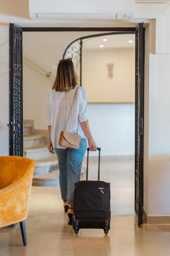 a woman pulling a suitcase in front of a mirror at Hôtel Du Golfe in Ajaccio