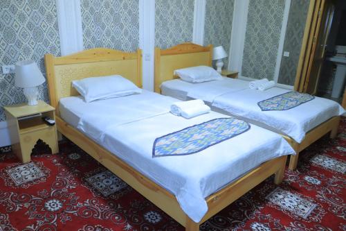 dos camas sentadas una al lado de la otra en una habitación en Hotel ALISHER, en Bukhara