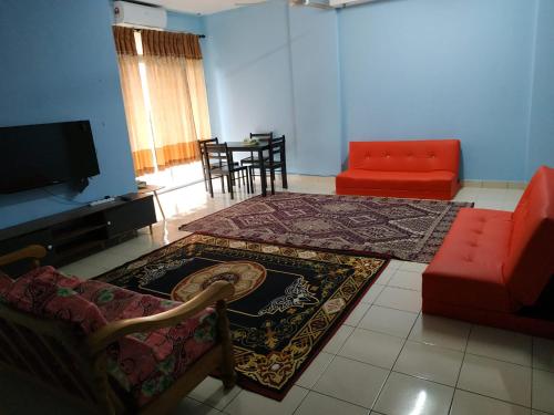 a living room with a red couch and a rug at budget Homestay and selesa with big swimming pool in Mantin