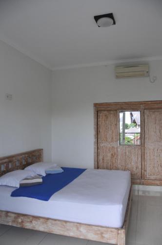 a bedroom with a bed with a wooden headboard and a window at The Hostel Canggu in Canggu
