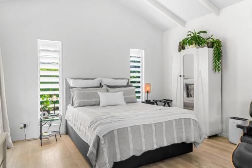 una camera da letto bianca con un letto e uno specchio di The Cabin - Mangawhai Heads Studio a Kaiwaka
