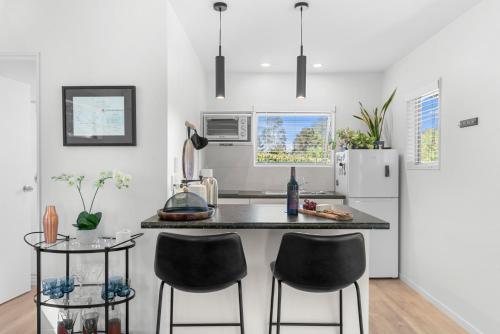 una cucina con bancone, 2 sedie e frigorifero di The Cabin - Mangawhai Heads Studio a Kaiwaka